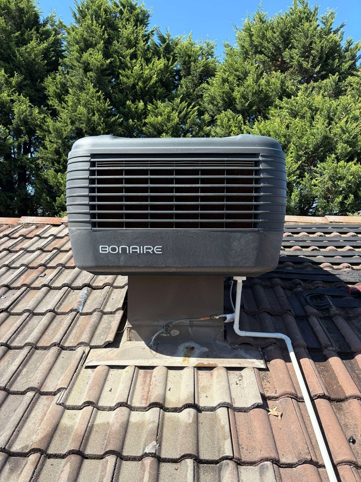 Bonaire evaporative cooler on a tiled roof with trees behind
