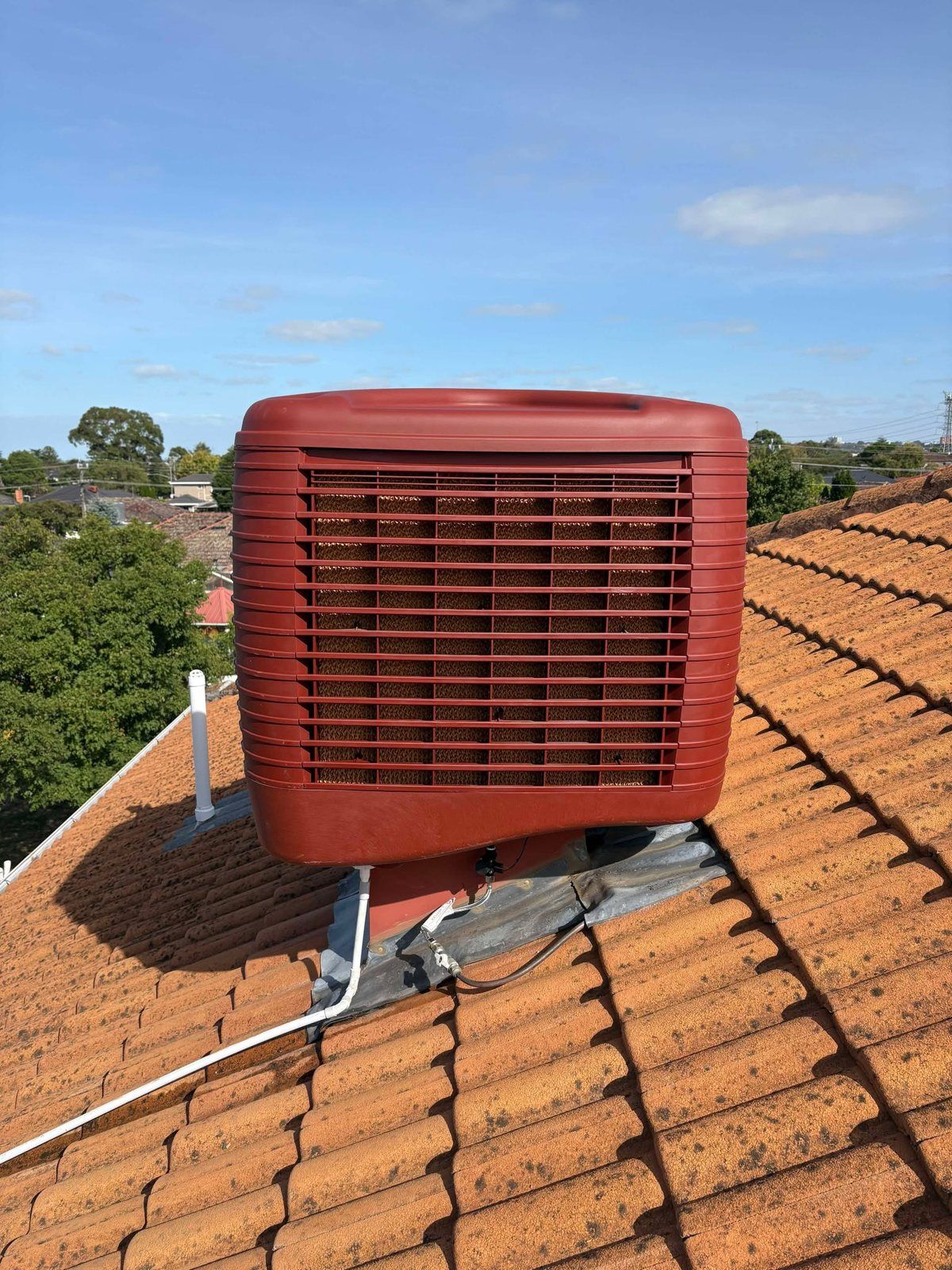 Evaporative cooler on an orange tiled roof