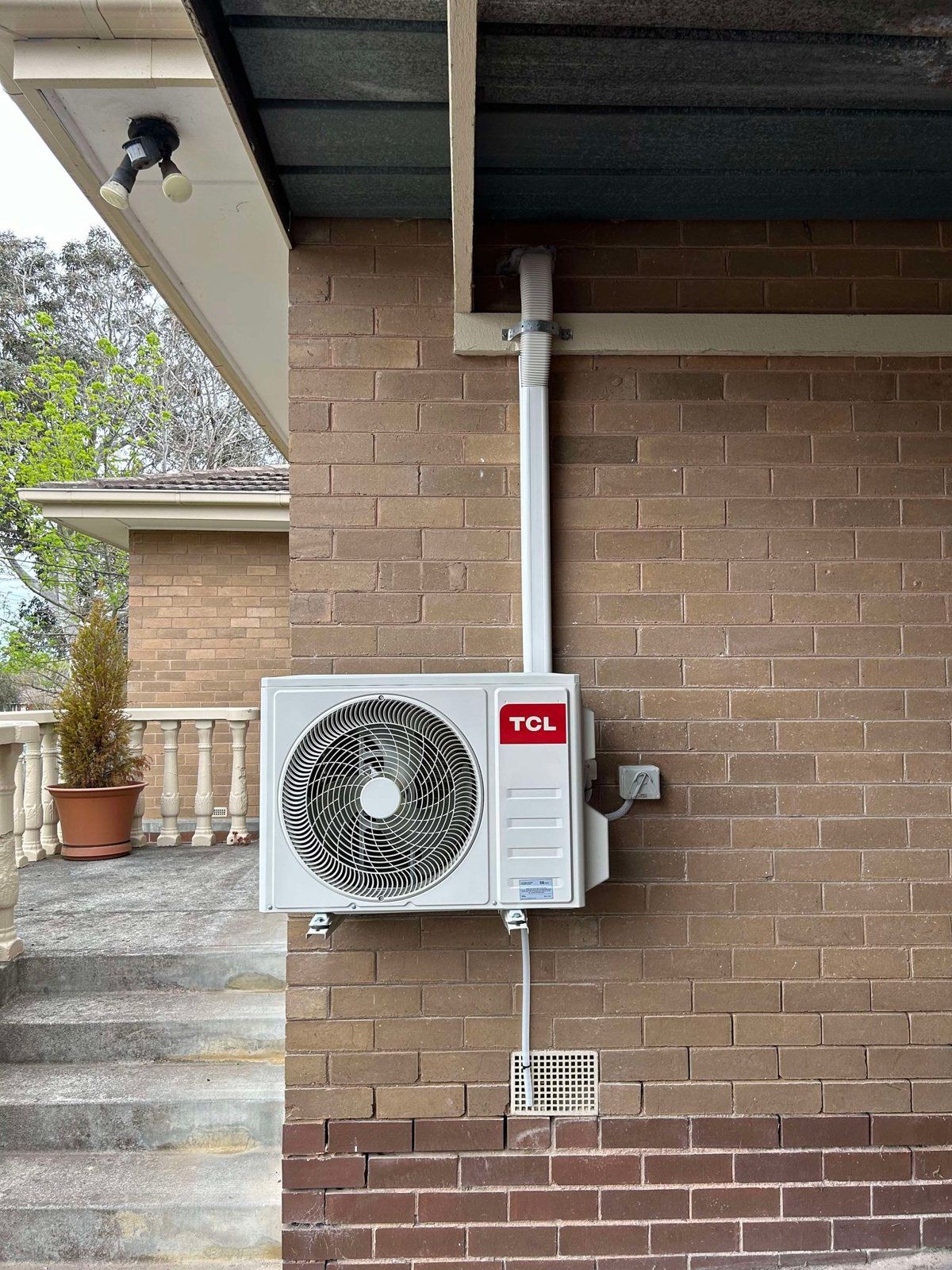 TCL outdoor unit on a brick wall with tidy covered pipework