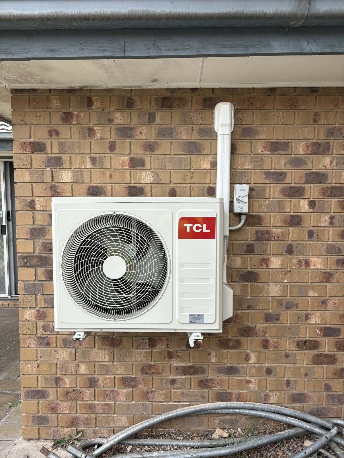 TCL split system outdoor unit mounted on a brick wall